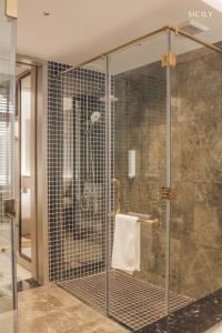 a shower with a glass enclosure in a bathroom at Sicily Hotel Grand World Phú Quốc in Phu Quoc