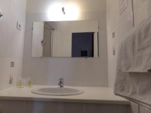 La salle de bains blanche est pourvue d'un lavabo et d'un miroir. dans l'établissement Ashley Hôtel Le Mans Centre Gare, au Mans