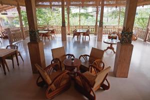 un comedor con mesas y sillas y una habitación con árboles en Blue Harbor Beachfront Villas & Resto, en Nusa Penida