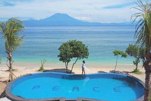 una mujer caminando por una piscina junto a la playa en Blue Harbor Beachfront Villas & Resto, en Nusa Penida