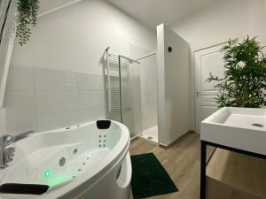 een witte badkamer met een bad en een wastafel bij Capsule Roubaix/Lille Balneo*Home cinéma*Billard in Roubaix