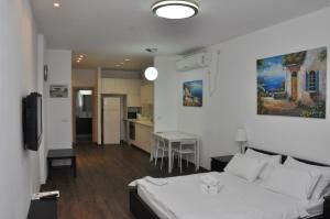 een slaapkamer met een wit bed en een keuken bij Star Apartments - Petah Tiqwa in Petach Tikwa
