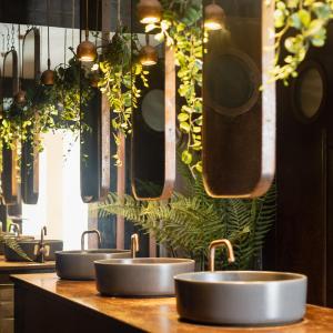 a row of sinks in a kitchen with plants at Estate Spa - Boutique Hotel in Rechovot