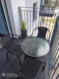 a glass table and chairs on a balcony at Apartament Mazury Węgorzewo in Węgorzewo