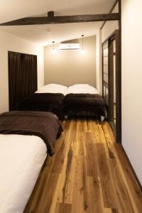 2 letti in una camera da letto con pavimento in legno di Cominka Yufuin a Yufu