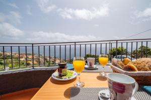 un tavolo con bicchieri di succo d'arancia e pane su un balcone. di Casa do Miradouro -Fantástico Estúdio a Santa Cruz
