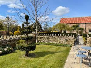 a garden with a stone fence and a table and chairs at Elm Tree Cottage in Salton