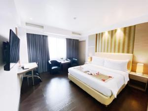 a hotel room with a large bed and a desk at Orchardz Hotel Industri Jakarta Kemayoran in Jakarta