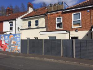 a fence in front of a house with a mural at Contractor friendly from 'TOBS Norwich' in Norwich