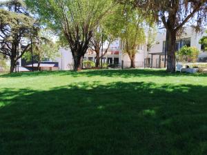 un campo de césped verde con árboles y un edificio en Giladi Hotel, en Kfar Giladi