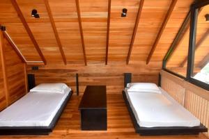 two beds in a room with wooden walls at Manuka Hillwood Hotel in Nuwara Eliya