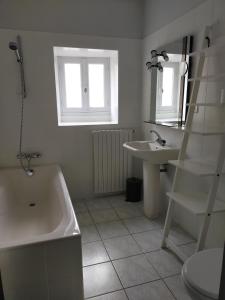 Baño blanco con bañera y lavamanos en Gîte Les Pieds dans l'Olt - Ultreïa, en Estaing