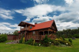 Cabaña de madera con techo rojo en un campo en Kurpiowska Chatka, en Stanisławowo