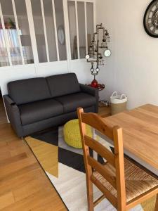 ein Wohnzimmer mit einem schwarzen Sofa und einem Tisch in der Unterkunft Le bruit des vagues in Berck-sur-Mer