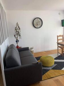 ein Wohnzimmer mit einem Sofa und einer Uhr an der Wand in der Unterkunft Le bruit des vagues in Berck-sur-Mer