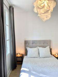 een slaapkamer met een bed, een raam en een kroonluchter bij T2 Montpellier centre, climatisé in Montpellier