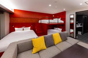 um quarto com 2 camas e um sofá com almofadas amarelas em GOLD STAY Nagoya Sakae ゴールドステイ名古屋栄 em Nagoia