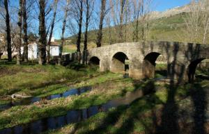 a stone bridge over a river in a field at Al-Andalus Alojamentos in Marvão