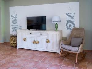 ein Wohnzimmer mit einem TV und einem weißen Schrank in der Unterkunft POP'S PLAGE APPARTEMENT in Le Gosier
