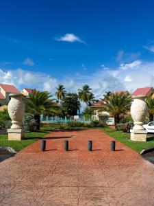 einen roten Backsteinweg mit Statuen vor den Häusern in der Unterkunft POP'S PLAGE APPARTEMENT in Le Gosier