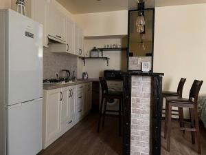 a kitchen with white cabinets and a counter with chairs at АpartmentAnna in Odesa