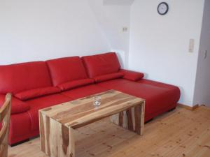 ein rotes Sofa im Wohnzimmer mit Couchtisch in der Unterkunft Schleisicht in Winnemark