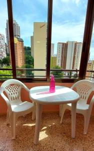 ベニドルムにあるEdificio Cadiz Benidormのテーブルと椅子2脚(ピンクのボトル付)