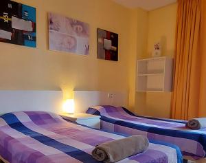 ベニドルムにあるEdificio Cadiz Benidormの紫と青のストライプを用いた客室内のベッド2台