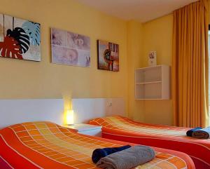 twee bedden in een kamer met oranje en geel bij Edificio Cadiz Benidorm in Benidorm