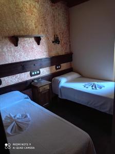Habitación de hotel con 2 camas con sábanas blancas en Casa rural "Matela", en Prado