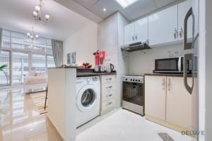 a kitchen with white cabinets and a washer and dryer at Gentle Studio in Uniestate Sports Tower Dubai Sports City by Deluxe Holiday Homes in Dubai