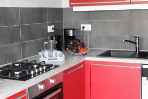 cocina con armarios rojos, fogones y fregadero en Appartement entre Sisteron et Gorges de la Méouge " Les Hauts de Toscane ", en Ribiers