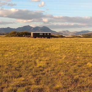 a house in a field with mountains in the background at Vittorio, en Llohue in Villa Ventana