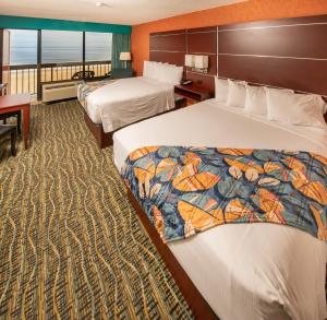 a hotel room with two beds and a balcony at The Breakers Resort Inn in Virginia Beach