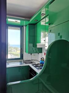 eine grüne Küche mit einem Waschbecken und einem Fenster in der Unterkunft Il Gabbiano casa al mare in Bisceglie
