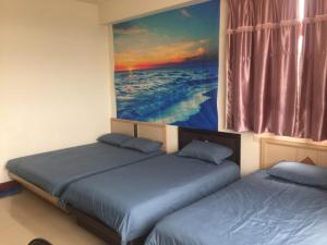 2 camas en una habitación con un cuadro en la pared en 美麗的民宿 可電洽民宿, en Beigan