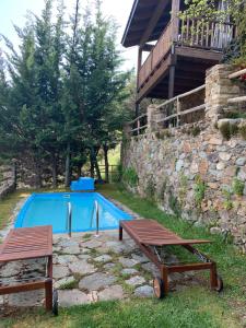 a swimming pool with two picnic tables next to a building at Casa Rural Pirineu Nevà in Nevà