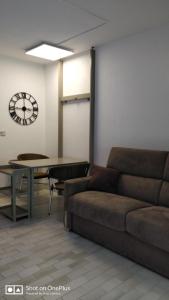 salon z kanapą i zegarem na ścianie w obiekcie STUDIO RDJ TERRASSE PISCINE SANARY SUR MER w mieście Sanary-sur-Mer