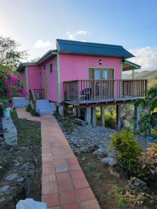 una casa rosa con una pasarela delante de ella en Tropical Paradise View, en Anse La Raye