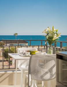 Sunny modern Apartment Perfect located في إِستيبونا: طاولة بيضاء وكراسي على شرفة مع المحيط