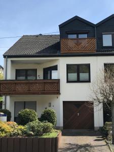 a white house with a wooden fence and a brown garage at Ferienwohnung Brinkmann 4**** mit Moselblick in Dieblich