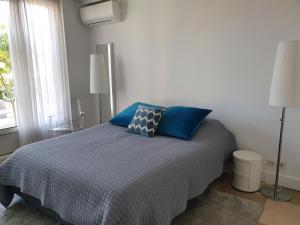 Appartement Centre ville carré d'Or في مونت كارلو: غرفة نوم مع سرير ووسائد زرقاء ونافذة