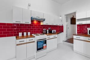 una cocina con armarios blancos y una pared de ladrillo rojo en Staywhenever TS- 4 Bedroom House, King Size Beds, Sleeps 9, en Stoke on Trent