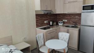 uma pequena cozinha com uma mesa branca e cadeiras em Apartment NATALIA in apart-otel RESIDENC em Batumi