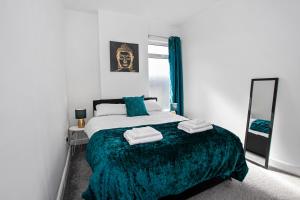 a bedroom with a bed with a green blanket and a mirror at Staywhenever LS- 4 Bedroom House, King Size Beds, Sleeps 9 in Stoke on Trent