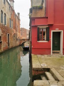 ヴェネツィアにあるBlueYellow home in Cannaregio Air conditioning WiFiの都市運河の横の赤い建物