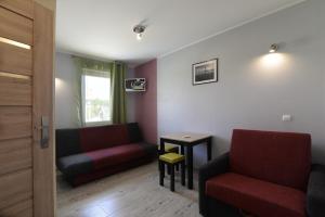 a living room with two red chairs and a table at APARTAMENT JAN-53 Krynica Morska in Krynica Morska