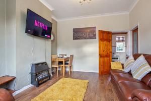 a living room with a couch and a television on a wall at Staywhenever NWT- 4 Bedroom House, King Size Beds, Sleeps 9 in Stoke on Trent