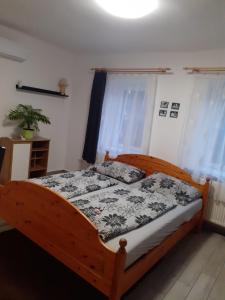 1 dormitorio con cama de madera y edredón blanco y negro en Oázis Apartman, en Sárospatak