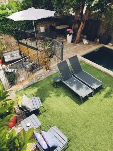 a backyard with a pool with chairs and an umbrella at La Maison Grivolas Appartements et Maison d'hôtes in Avignon